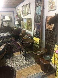Warehouse view showing the variety of offerings at this final sale including tables, lamps, paintings, textiles, storage vessels, trunks, and rugs.