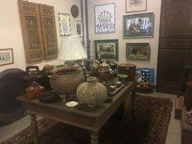 Wonderful Indonesian farm table with single board top holding a wide selection of Asian ceramics, basketware, boxes, etc. Note fine oriental rug and to the right, a very large wall screen with lattice top and paneled base.
