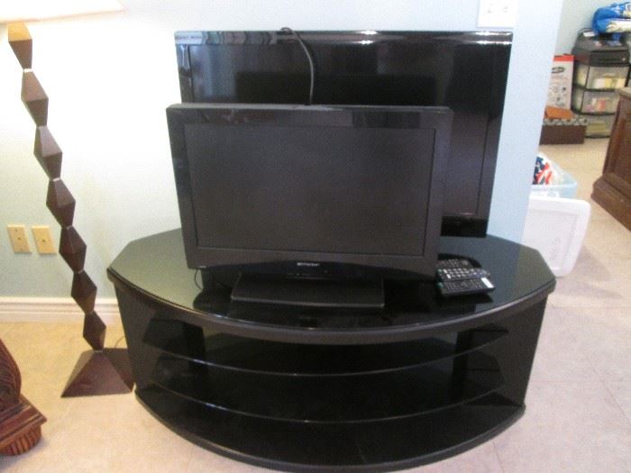 2-Flat-Screen TV's, 37" and 26", sitting on a TV Stand with a glass top