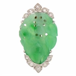 Art Deco Platinum Carved Jadeite Diamond Brooch with 14K White Gold Pin Stem: An Art Deco platinum brooch exhibiting a prong-set jadeite craved to depicting a floral design and diamonds set to the sides. The brooch features a 14K white gold pin stem to the verso.