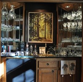 Wet bar in the study with a wide assortment of bar ware and a painting entitled "Rainforest" by contemporary artist