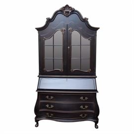 Dutch Rococo Style Secretary Desk Cabinet: A Dutch Rococo style secretary desk cabinet in a black lacquer and gilt finish with worn appearance. The arched and molded pediment features a carved shell, above two shaped doors with divided glass panels, which open to a lighted interior with two glass shelves, above a slanted lid, revealing a divided interior with four small drawers. Below are three drawers with cast brass foliate handles, above claw-and-ball feet.