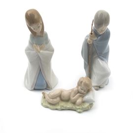Lladró "Nativity" Porcelain Figurines: A group of the Lladro porcelain figurines from the Nativity collection. Each piece was designed by Lladro artist Juan Huerta and is in the form of a baby Jesus sleeping a a straw bed, Mary, and Saint Joseph watching over him. The pieces are marked to the underside “Lladro, Hand Made in Spain, Daisa." Baby Jesus, Saint Joseph, and Mary were first released in 1969 and retired in 2001, numbers 01004670, 01004671, and 01004672 in the Lladró historical catalog.