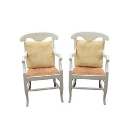Pair of Pottery Barn "Napoleon" Arm Chairs with Pillows: A pair of Pottery Barn “Napoleon” arm chairs. These wooden pieces are painted cream with rush seats woven in a traditional pattern. The arm chairs feature a keyhole splat and saber feet. Two faux-suede yellow accent pillows are included.