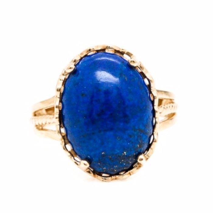 10K Yellow Gold Lapis Lazuli Ring: A 10K yellow gold lapis lazuli ring. This ring showcases a center lapis lazuli held in a scalloped setting mounted atop split shoulders with rope accents.