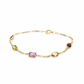 14K Yellow Gold Garnet, Citrine, Amethyst and Peridot Bracelet: A 14K yellow gold garnet, citrine, amethyst and peridot bracelet. This figaro chain link bracelet features stations of bezel set gemstones. Stones include garnet, citrine, amethyst and peridot. Shapes include pear, marquise, oval, emerald cut and faceted oval.