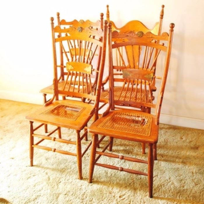 Walnut and Oak Dining Chairs: A group of four walnut and oak chairs. They have curved, decorated top rails over turned spindles gathered in the center with a horizontal splat. They have cane seats, and tapered and turned legs joined by double box stretchers. One is an arm chair with a different design to the back rest; it has tall finials, bead accents, and a vase-shaped center splat flanked by straight spindles.