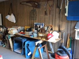 Miscellaneous on wall and table of garage, portable/travel dog kennels.