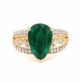 18K Yellow Gold Emerald and Diamond Ring: An 18K yellow gold emerald and 0.52 ctw diamond ring. This features a central pronged pear faceted emerald gemstone with split diamond encrusted milgrain shoulders, accented by central bezel set diamonds within the openwork leading to a smooth high polish shank.