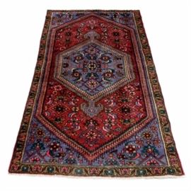 Hand-Knotted Persian Kurdish Bijar Area Rug: A hand-knotted Persian Kurdish Bijar area rug. This wool carpet is hand-knotted in a palette of cranberry, cornflower blue, teal, burgundy, ocher, pink, and pale mint. It features a central cornflower blue hexagonal pendant medallion on a cranberry colored lozenge with sawtooth edges. The field and corner spandrels are patterned with geometric herati motifs and the rug is framed by a carnation meander border.Finishing the rug are overcast selvedges and natural warp fringe to the ends. Labeled to the underside “Made in Iran”.