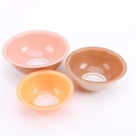 Vintage Pyrex Nesting Bowls: A collection of vintage nesting bowls by Pyrex, circa 1980s. These three mixing bowls are peach, mocha, and yellow with clear round bases. They are marked to the underside “Pyrex”.