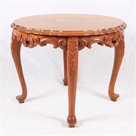 Figural Inlay Accent Table: A round wooden accent table with figural inlay. This table features a wood veneered inlay of a teapot and cup to the top with scalloped edges over a highly carved apron. It stands on carved cabriole legs on pad feet.