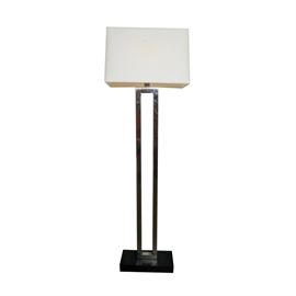 Contemporary Rectangular Floor Lamp: A contemporary rectangular floor lamp. The floor lamp features a rectangular shaped white fabric shade atop a chrome finish column composed of four bars that come together to form the outline of a rectangle. The lamp rests on a rectangular shaped black base.