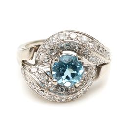 14K White Gold Blue Topaz and 1.00 CTW Diamond Bypass Ring: A 14K white gold blue topaz and 1.00 ctw diamond bypass ring. This features a pronged blue topaz to the center of a bypass of channeled diamonds.