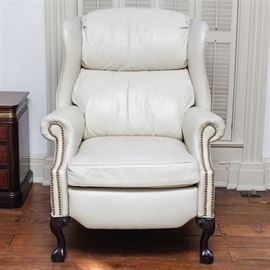Vintage Chippendale Style Leather Wing Back Recliner: A vintage Chippendale style wing back recliner. This piece is upholstered in white leather and studded with brass nail heads at the armrests. It has a removable seat cushion, and the chair sits on wooden cabriole front legs with carved knees and claw-and-ball feet.