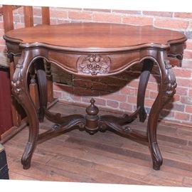 Antique Walnut Turtle Table: An antique turtle table. This piece is constructed from walnut, and it features a beveled turtle top over a serpentine apron with relief carved cherry blossoms. it rises on four cabriole legs with acanthus leaf carved knees and whorl feet, and the legs are joined by S curl stretchers and a center finial.