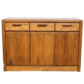 Vintage Oak Buffet: A vintage buffet. This piece is constructed from oak, and it features one broad drawer with dividers to its interior. Below is a cabinet to the left and a double door cabinet to the right which opens to reveal an interior shelf.