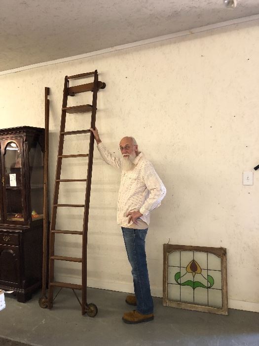 Antique Oak Library ladder on wheels . The gentleman standing is over 6 ft tall to compare size . It comes with wall  slide molding . This is only one  Stained Glass Window. There’s a lot of Stained Glass
