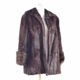 Wolf & Dessauer Dyed Muskrat Fur Coat: A Wolf & Dessauer dyed muskrat fur coat. This dyed coat has two lapels, a top button closure and cuffed sleeves. It has a brown floral embroidered lining and a white “Wolf & Dessauer” label.