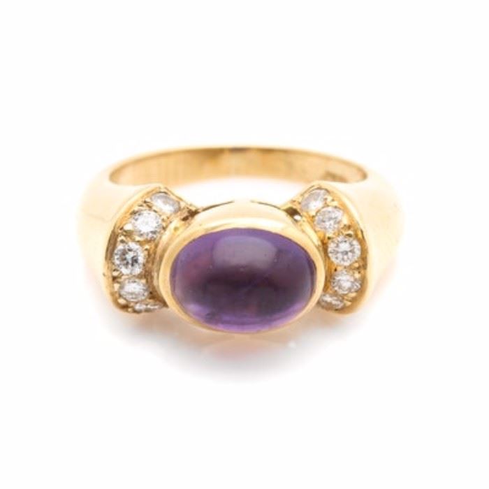 18K Yellow Gold Amethyst and Diamond Ring: A 18K yellow gold amethyst and diamond ring. This ring showcases an amethyst center, accented by twelve diamonds adorned atop the flared and ridged shoulders. The total carat weight of all diamonds included is 0.36 ctw.