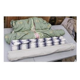 Variety of Drapery Panels: A variety of drapery panels. The variety includes panels in green with yellow and pink dragonflies and accents, a blue and white striped Roman shade panel, and a gray pleated curtain panel. The custom made draperies are lined. Also included are several cream colored tassels.