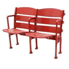 Pair of Crosley Field Seats: A pair of Crosley Field seats. The pair of seats are self-standing (they are not mounted on a base) and have been painted a bright red. Crosley Field was the home field of the Cincinnati Reds (baseball and football teams), the Cincinnati Bengals (1937, 1941-1943), Cincinnati Tigers, Buckeyes and the Clowns (all three were Negro League Teams). The seats are made of wood with a metal frame. Redland Field was renamed Crosley Field in 1934; Crosley was the last name of the Powel Crosely Jr., the owner of the Reds from 1934-1961.