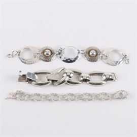 Two Sterling Silver Bracelets Made in Mexico and a Fancy Link Sterling Bracelet: A group of three sterling silver bracelets. Two of these were made in Mexico, one consisting of four heavy, oversized links with latch closure, the second bearing Taxco hallmarks designed as a series of hammered discs, three pierced and two holding round sterling cabochons within gold wash roped bezel settings to center. The third bracelet offers a series of large, fancy interlocking link segments and was made in China. Each piece is hallmarked as sterling silver, and the total weight, inclusive of all materials, is 2.960 ozt.