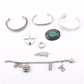 Sterling Modernist Style Sterling Penannular Brooch, Mexican Cuff and More: A selection of jewelry that is mostly sterling silver with one costume brooch set with green glass. Featured among these is a modernist style penannular brooch with a green dyed chalcedony cabochon, bearing post-1976 British sterling hallmarks. Among the three cuff bracelets is a polished piece with wide band made in Mexico, and a smaller polished piece marked “CI 925.” There is also a charm bracelet with five charms, a sterling ring, and Ciani sterling twist brooch.Each piece is tested or hallmarked as sterling silver and the total weight inclusive of all materials is 4.040 ozt.