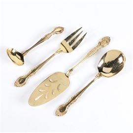 Gold Tone Stainless Steel Scroll-and-Flower Edge Serving Utensils: A set of four gold tone stainless steel serving utensils including one cold meat fork, one pierced pie server, one casserole spoon, and one gravy ladle. Each item features a curved handle with scroll-and-flower edges and a plume tip.