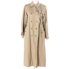 Women's Burberry Trench Coat: A women’s Burberry trench coat. This khaki-colored, double-breasted trench features shoulder epaulets, a hook and eye closure at the collared neck, button closures, a belted waist, buttoned besom pockets, adjustable cuffs, center vent and a classic Burberry plaid lining. It is labeled to the interior, “Burberry made in England”.