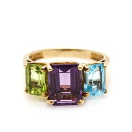10K Yellow Gold Amethyst, Peridot, and Blue Topaz Ring: A 10K yellow gold amethyst, peridot, and blue topaz ring. This ring features a center, amethyst stone with a peridot to one side, and a blue topaz to the other that lead to the tapered, high polish shoulders.