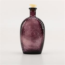 George Washington Flask: A George Washington flask. This pressed glass bottle has a slight purple amethyst tinge with an embossed American Bald Eagle on one side and on the reverse is a bust of General George Washington with a white stopper. No discernible makers marks are noted.
