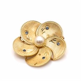 14K Yellow Gold Cultured Pearl and Sapphire Floral Brooch: A 14K yellow gold cultured pearl and sapphire floral brooch. This brooch features a satin floral motif housing a cultured pearl in the center and sapphire accents on each petal with a diamond-cut border.