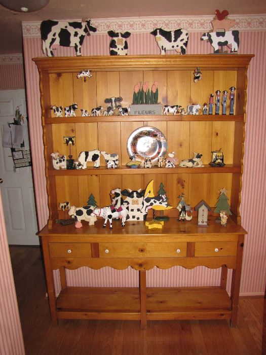 Display hutch with decorative cow and bovine items, all for sale.