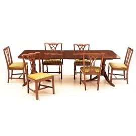 Duncan Phyfe Style Dining Table and Chairs: A Duncan Phyfe style dining table with six chairs. The table features rounded edges and rests over two, urn style pedestal bases with brass caped saber legs. Includes six Chippendale style chairs, five side chairs and one armchair, with pierced splats, upholstered seats finished in a textured, striped pea green fabric and square legs with H stretchers. Includes three leaves.