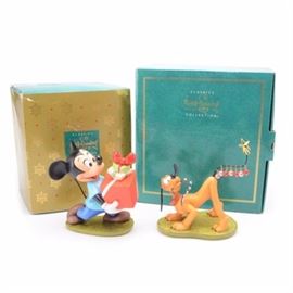 Mickey and Pluto Walt Disney Collection Christmas Figurines: A pair of Walt Disney Collection porcelain figures featuring Disney’s famous characters Pluto and Mickey Mouse. This lot includes Pluto Helps Decorate and Presents for my Pals both feature the Society logo and are impressed with emblems that indicate their production date. Mickey has the impressed trowel indicating 1995 and Pluto has the sailor hat indicating 1996 production. Lot includes the original boxes. All are retired.