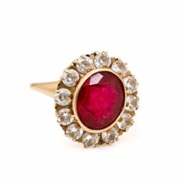 10K Yellow Gold Ruby and Cubic Zirconia Ring: A 10K yellow gold ruby and diamond ring. This ring features a crown of a faceted oval synthetic ruby surrounded by a halo of faceted round cubic zirconia.