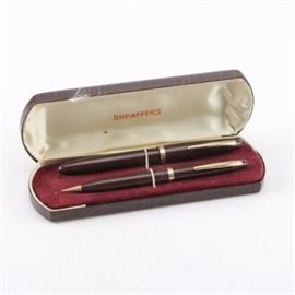 Sheaffer Pen and Pencil Set: A Sheaffer’s pen and pencil set, each featuring a brown resin barrel with gold tone clips and bands. They are each emboss marked “Sheaffer Pen Co.” to the barrels. The set is stored in its original faux alligator leather clamshell case.