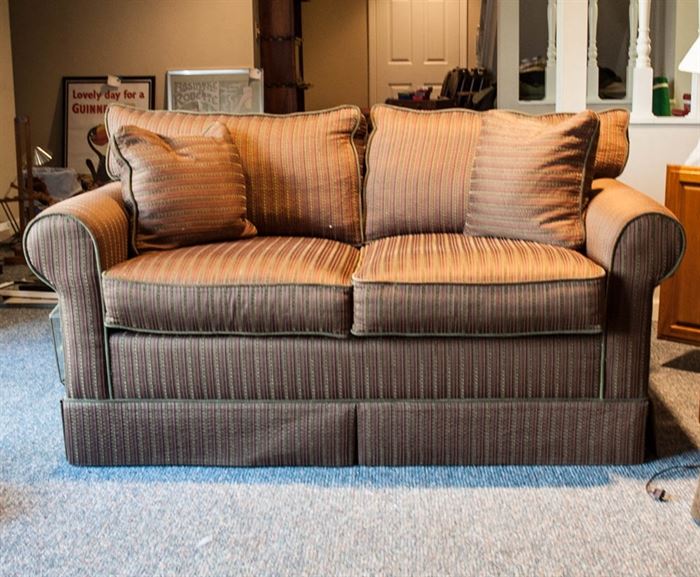Brown Striped Sofa by Norwalk: A brown sofa by Norwalk. This sofa has rolled arms, two removable seat cushions, two removable back cushions, and two matching accent pillows. The couch has a brown, orange, and gold vertical stripe design.