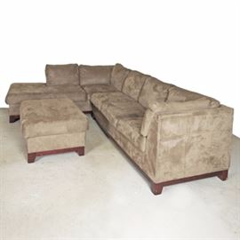 Micro-suede Sectional with Ottoman: A tan two-piece microsuede sectional sofa with an ottoman. Each section features a straight crest rail with attached back rest cushions and loose seat cushions. They stand on wooden tapered legs. A tag to the underside reads “Made by Stratford Company a division of Caye Upholstery”.