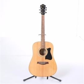 Ibanez Acoustic Guitar: An Ibanez Galvador acoustic guitar. This guitar is model V50-NT 3U-02 and serial number SA110901280. The piece features a natural finish, silver tone tuners, pick guard, and decorative stripes to soundhole. It is marked “Ibanez” on the headstock and interior.