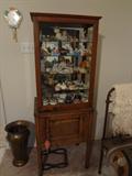 small cabinet with a curio cabinet setting on it containing small collectibles
