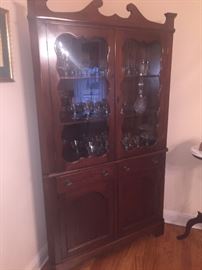 corner cabinet filled with vintage crystal stemware