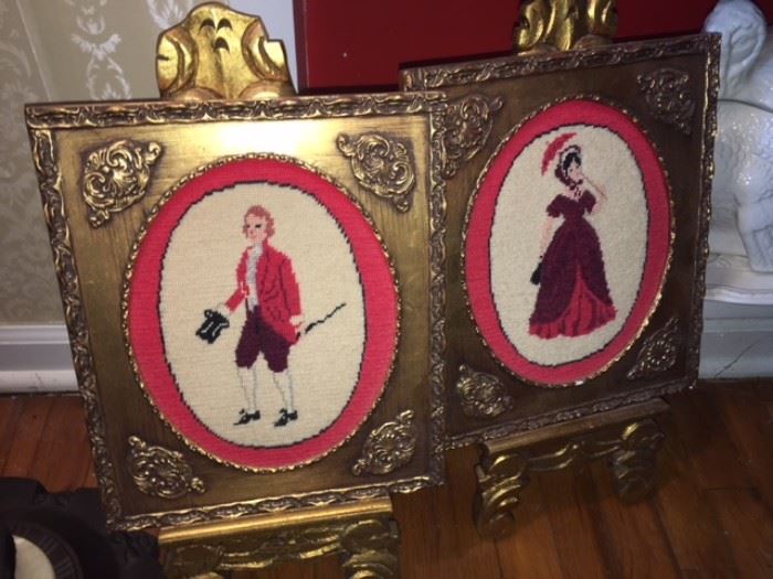 pair of cross stitch portraits with gold guild frames on gold wood easels