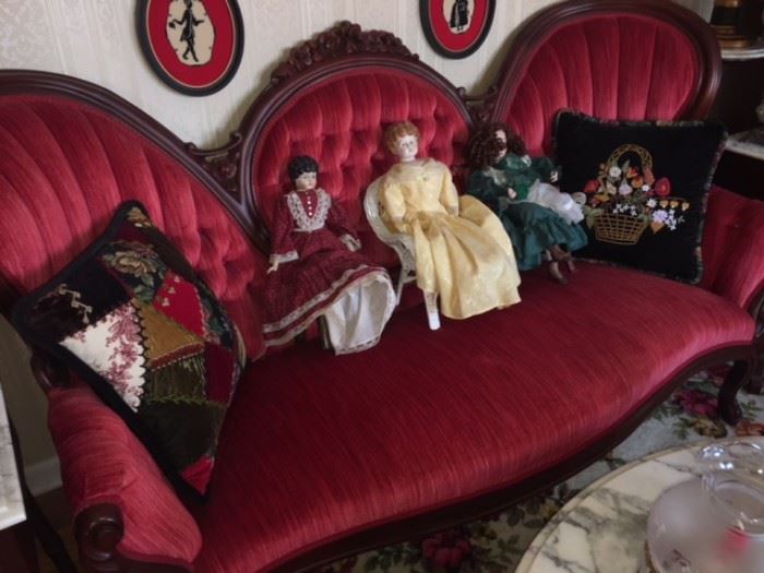 collection of porcelain dolls on sofa with hand made pillows made of quilting and cross stitching