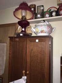 oak kitchen pantry with oil lamp with an assortment of  tins on top shelf