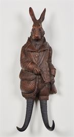 Black Forest 19C Carved Hunting Hare Rabbit Rack. Black Forest 19th century carved hunting hare rabbit rack. Carved wooden 19th century figural rabbit coat or hat rack. The antler and wood rack figure is carved in the form of a hunting hare with rifle slung on its back, with game catch bag on the side, standing on rams horn legs. Good condition, tip of the rifle barrel is broken off. Measures 19 inches long x 6 inches wide.