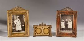 French 19C Ornate Brass Figural Picture Frames (3)     Group of 3 ornate 19th century French ormolu brass picture frames. The largest frame measures 9 inches high x 6.5 inches wide and has a crest with crossed torches and leaves. The next with a wooden ormolu mounted frame with a wreath-form crest. The smallest, 3.4 inches high, is a double ormolu mount with swan decoration. Good condition. All sold together as one lot. 