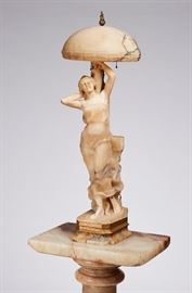 Italian 19C Marble Alabaster Nude Lamp & Pedestal    Late 19th century Art Nouveau marble lamp and pedestal. Lamp has a domed shade with embossed trim and flame finial raised over a standing draped female figure holding a urn atop a columnar base. Good condition, section of lamp base mounted with gilt wood. Lamp measures 40 inches high. Pedestal included with an overall measurement of 80.5 inches high x 15 inches wide x 21 inches deep.
