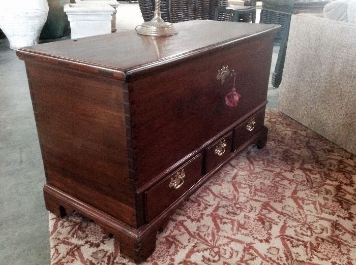 Side view of antique Pennsylvania dower chest on top a repeated palmette design carpet